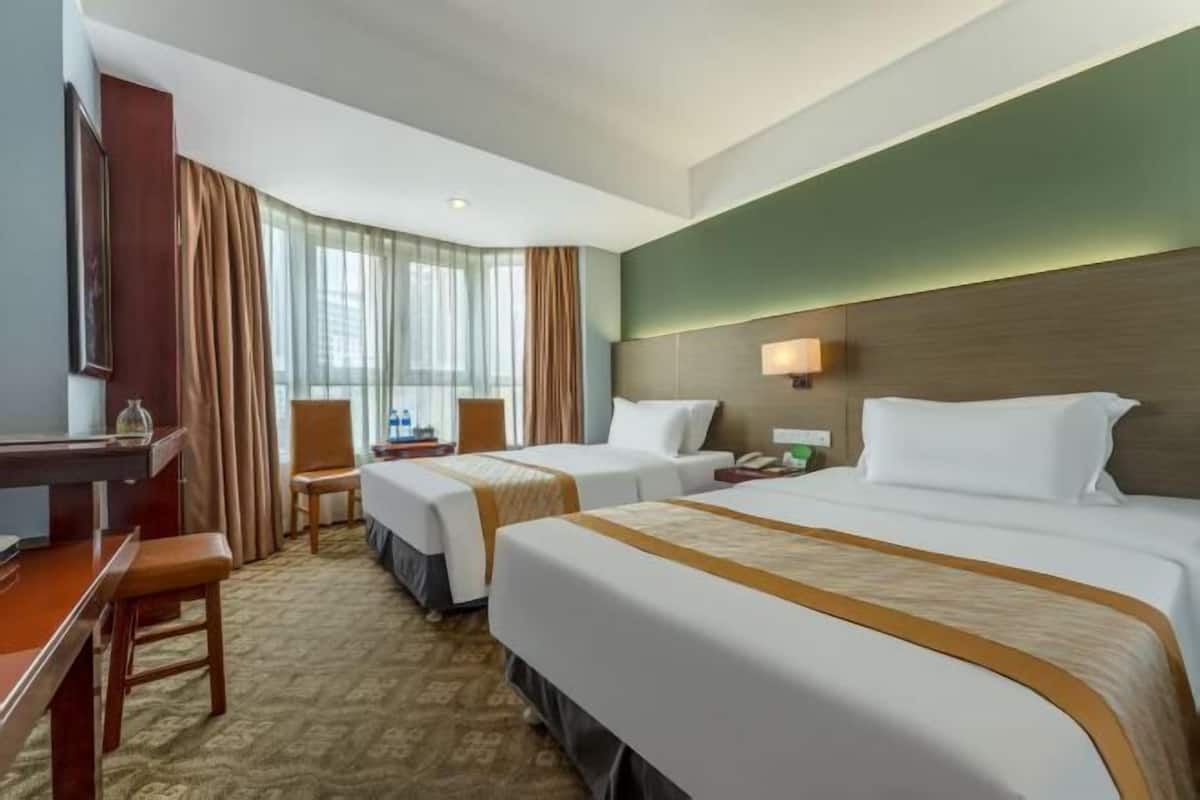 A hotel room with two beds, a desk, a chair, a lamp, and a view of the outdoors.