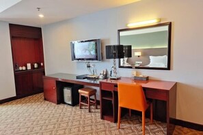 A hotel room with a wooden desk, a television, a mirror, and a patterned carpet. - Shunjing Hotel (Zhongshan)