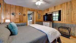 A bedroom with a bed, a ceiling fan, a dresser, and a TV.