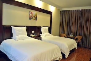 Quarto de hotel com duas camas, uma mesinha, duas cadeiras, um quadro na parede e uma cortina.