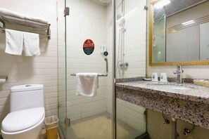 Casa de banho com sanita, cabine de duche em vidro, lavatório com bancada de granito e espelho com moldura dourada.