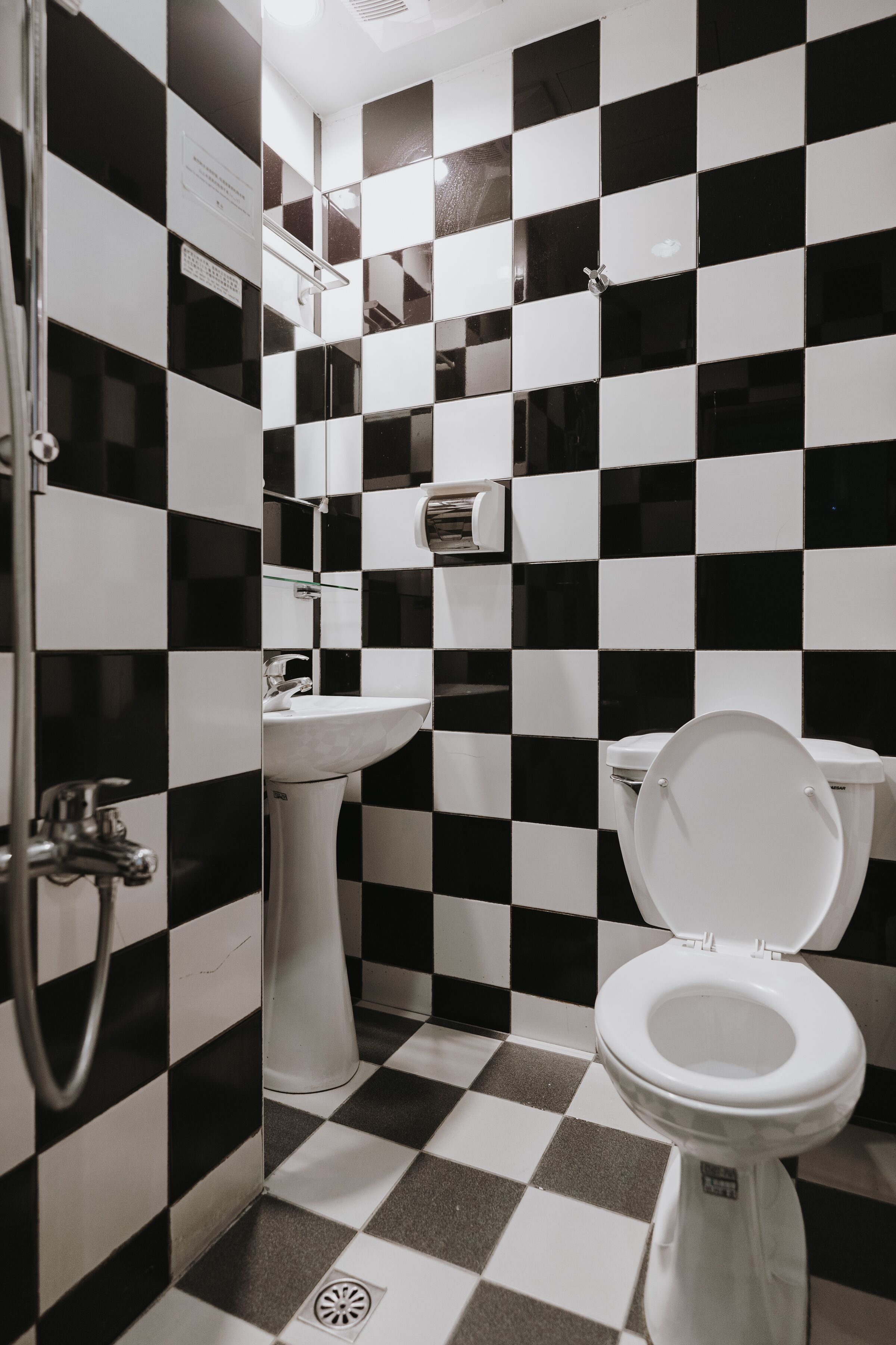 A bathroom with black and white checkered tiles, a white sink, and a toilet.