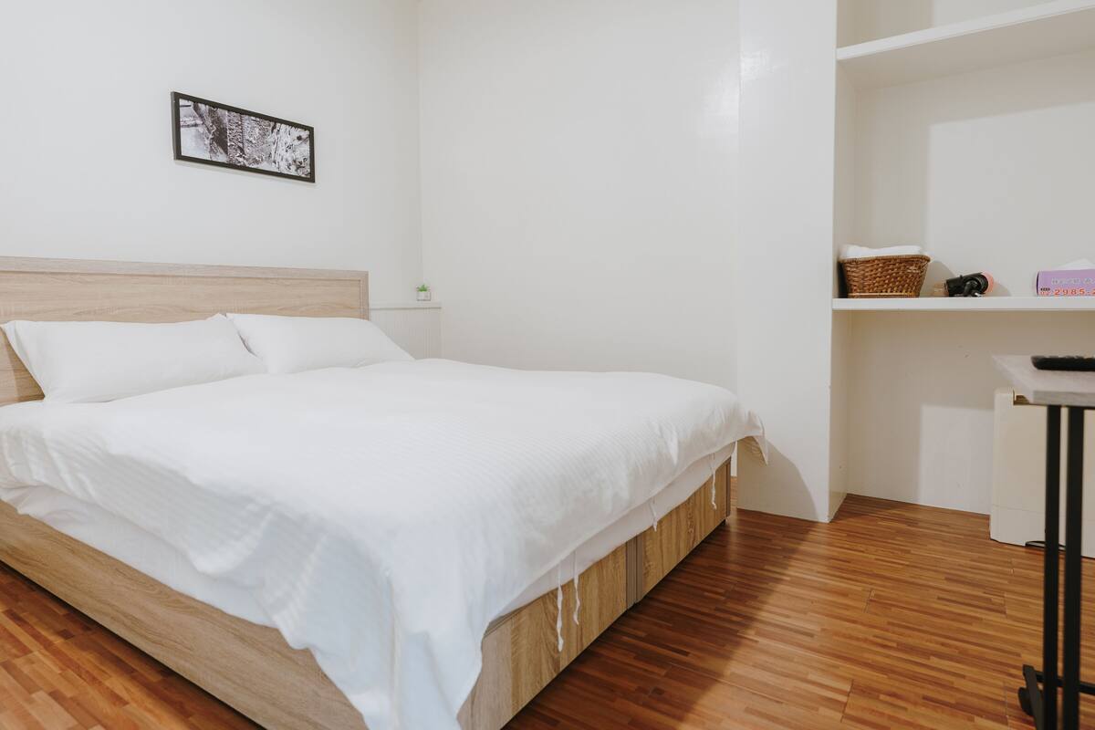 A neatly made bed with white linens, a wooden headboard, and a small bedside table with a lamp.