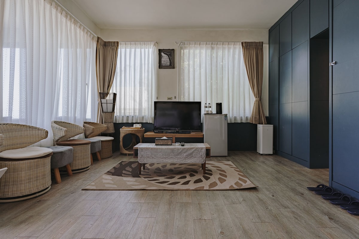 A living room with a TV, sofa, and chairs.