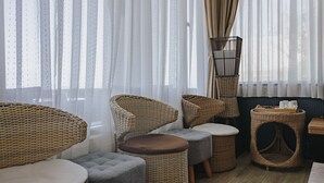 A room with wicker furniture, including chairs and ottomans, near a window with sheer curtains. - Mountain Traveler Inn (New Taipei City)