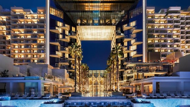 Un hotel moderno con un atrio central, varios pisos y una zona de piscina.