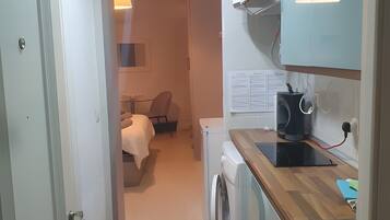A compact kitchen with a washing machine, a microwave, and a sink.