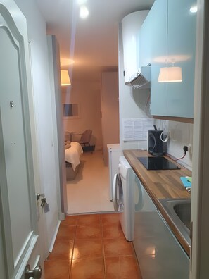 A compact kitchen with a washing machine, a microwave, and a sink.