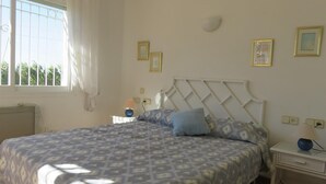 A bedroom with a bed, bedside tables, a window with curtains, and wall-mounted light fixtures. - Apartment 'Les Fonts 83' with Shared Pool, Private Terrace and Balcony (L'Estartit)