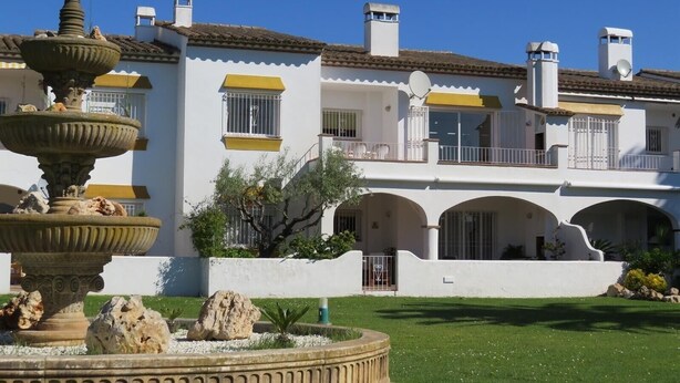 A multi-story building with a fountain, balconies, and a well-maintained lawn. - Apartment 'Les Fonts 83' with Shared Pool, Private Terrace and Balcony (L'Estartit)