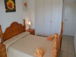 A bedroom with a wooden bed, a nightstand with a lamp, a wardrobe, and a door. - Villa "Medas Maura 8" with Pool, Wi-Fi, Balcony and Terrace (L'Estartit)