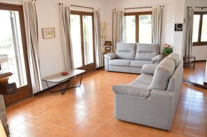 Una sala de estar con un sofá, una mesita y una planta en maceta.