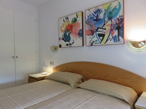 Une chambre à coucher avec un lit, deux tableaux, une lampe de chevet et une table de chevet.