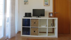 A living room with a TV, shelves, and wall art. - Apartments Miami II 307 with Mountain View, Pool, Wi-Fi & Garden (L'Estartit)