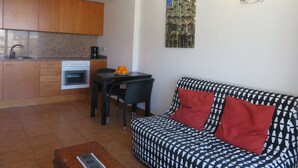 A compact living space with a kitchenette, a dining area, and a sofa with patterned cushions. - Apartments Miami II 307 with Mountain View, Pool, Wi-Fi & Garden (L'Estartit)