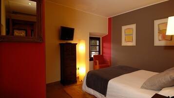 Un cuarto de hotel con una cama, televisión, cómoda y obras de arte en las paredes.