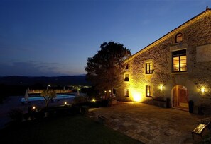 A stone building with a swimming pool, a bench, and a view of the mountains.