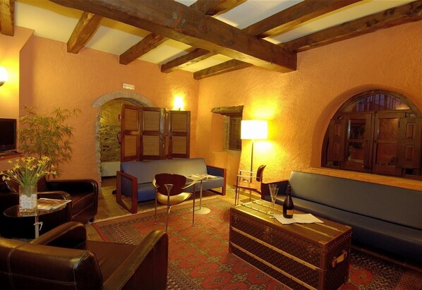 A cozy room with a wooden ceiling, a sofa, a table, and a lamp.
