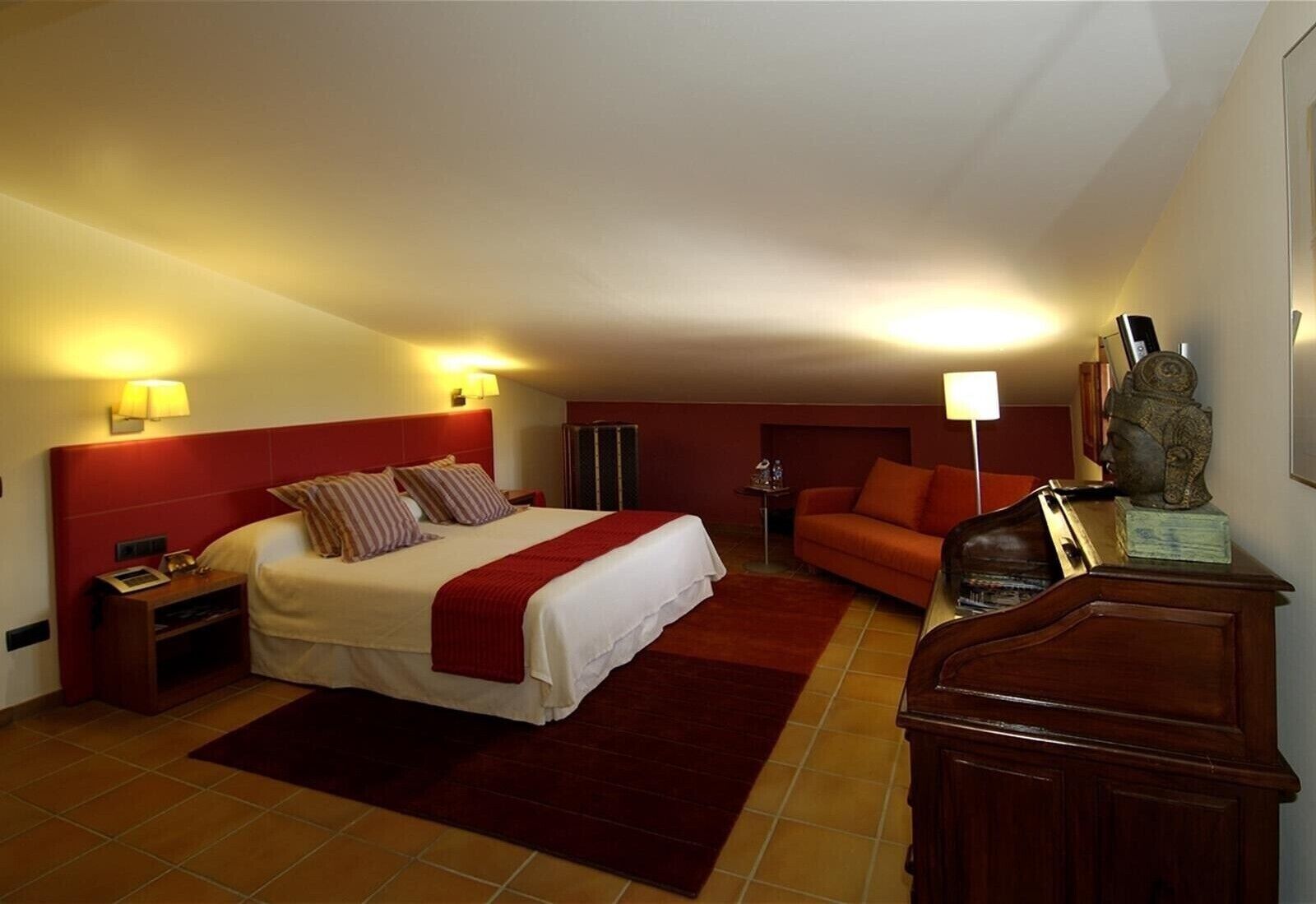 Une chambre d’hôtel avec un grand lit, un canapé, un bureau et une statue.