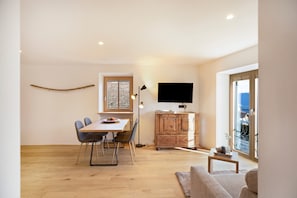 Un espacio habitable moderno con comedor, televisor y vistas al exterior.