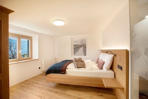 Un dormitorio con una cama de madera, una ventana, un radiador y una lámpara en el techo.