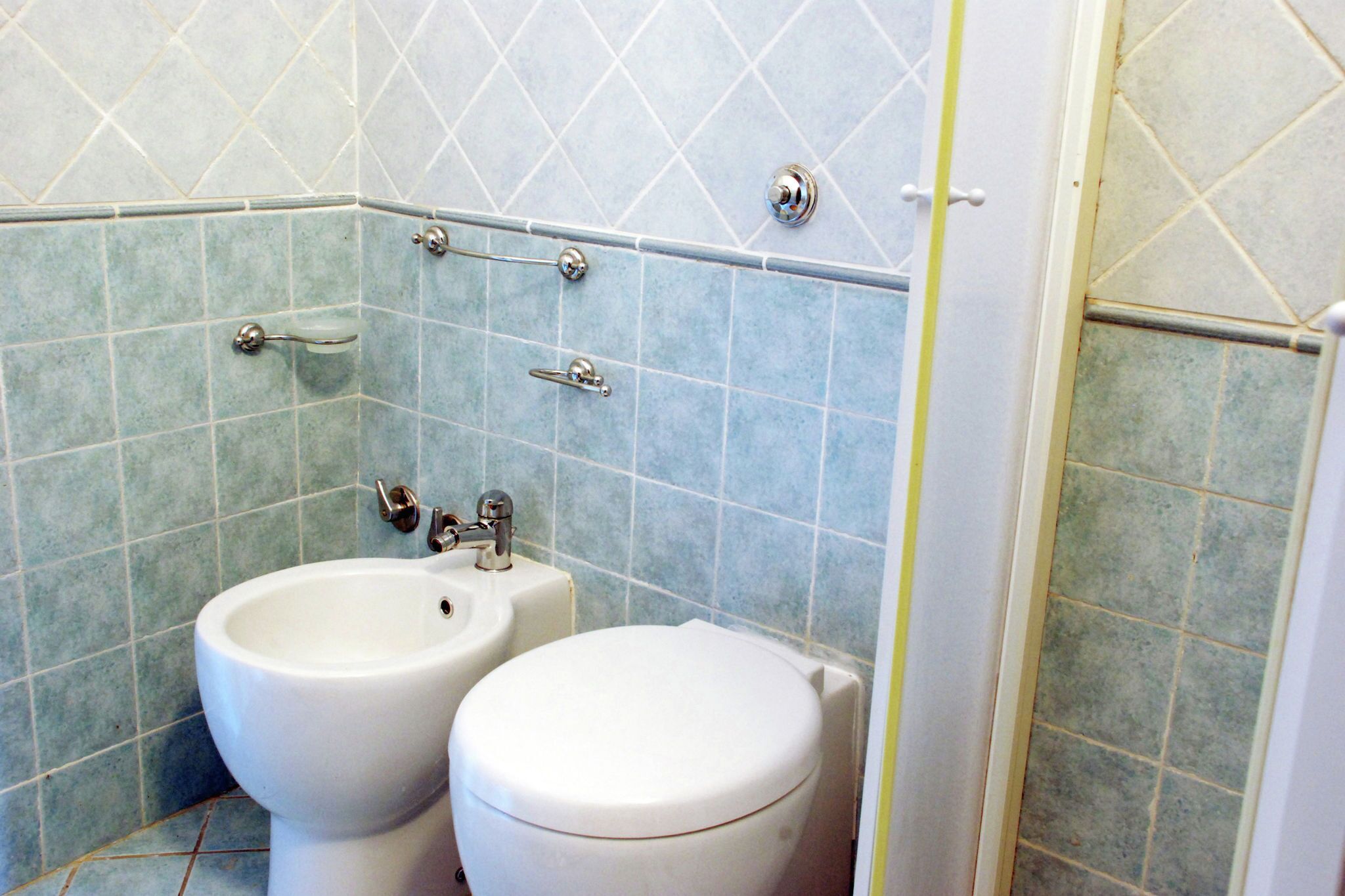 A bathroom with two toilets, a bidet, and a sink.
