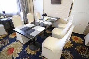 Ein Hotelzimmer mit kariertem Tisch, weißen Stühlen, einem Blumenteppich und einem Bett.