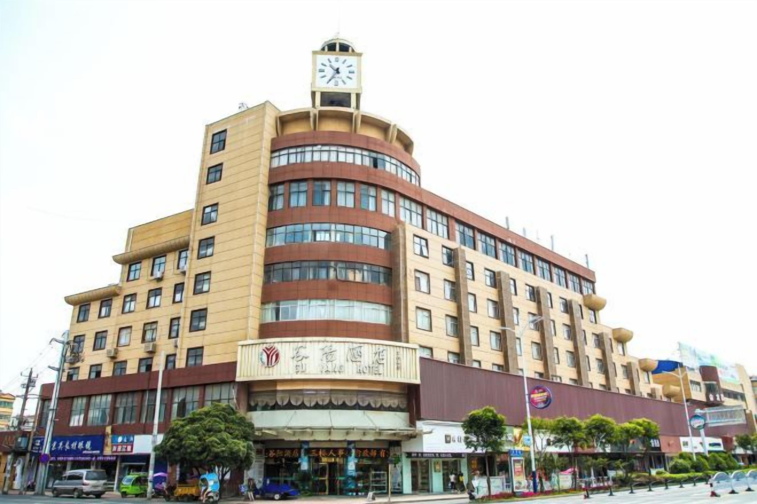 A multi-story building with a clock tower, featuring a ground-level commercial space with shops.