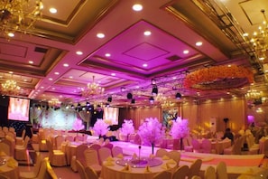 A banquet hall with round tables, a stage, and a chandelier. - Guyang Hotel (Guzhen)