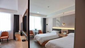 A hotel room with two beds, a desk, a chair, and a window. - Guyang Hotel (Guzhen)