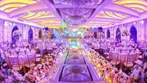 A banquet hall with round tables, a central floral arrangement, and a chandelier. - Guyang Hotel (Guzhen)