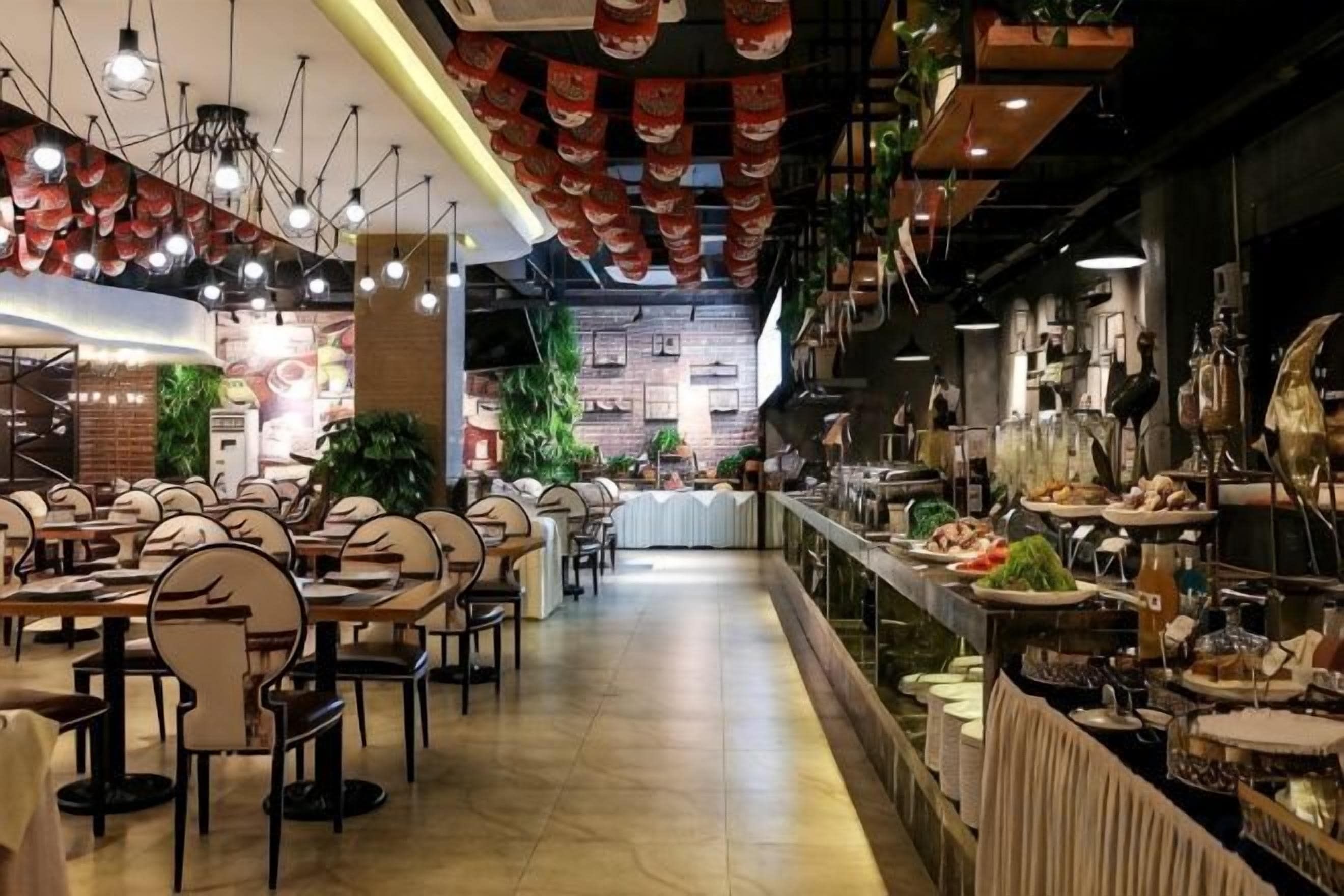 A restaurant with multiple dining tables and chairs, a bar area, and a counter with food displays.