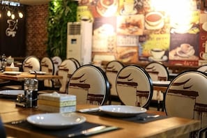 Interior de un restaurante con mesas, sillas y un pastel sobre la mesa.