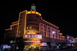 Un hotel de varios pisos con una torre de reloj, que cuenta con señalización iluminada.