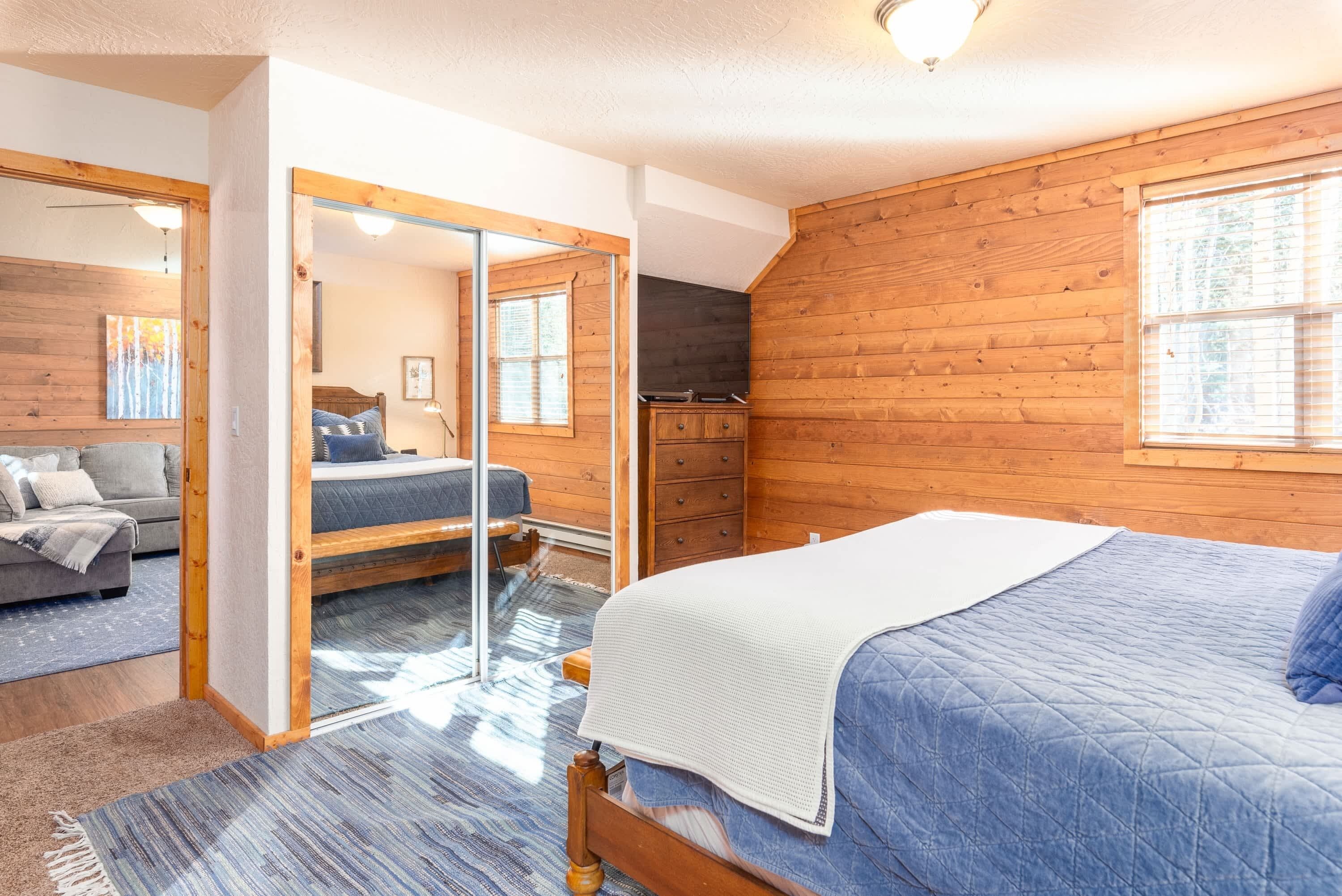 Un dormitorio con cama, cómoda, espejo y ventana.