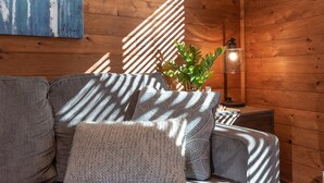 Ein gemütliches Zimmer mit einer Couch, einer Lampe und einer Pflanze.