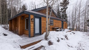 Eine Holzhütte mit Tür, Fenstern und einer Bank davor.