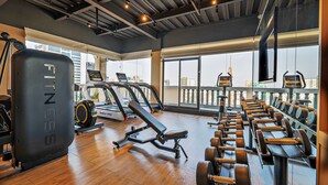 Een sportschool met cardioapparatuur, gewichtbanken en een grote spiegel.