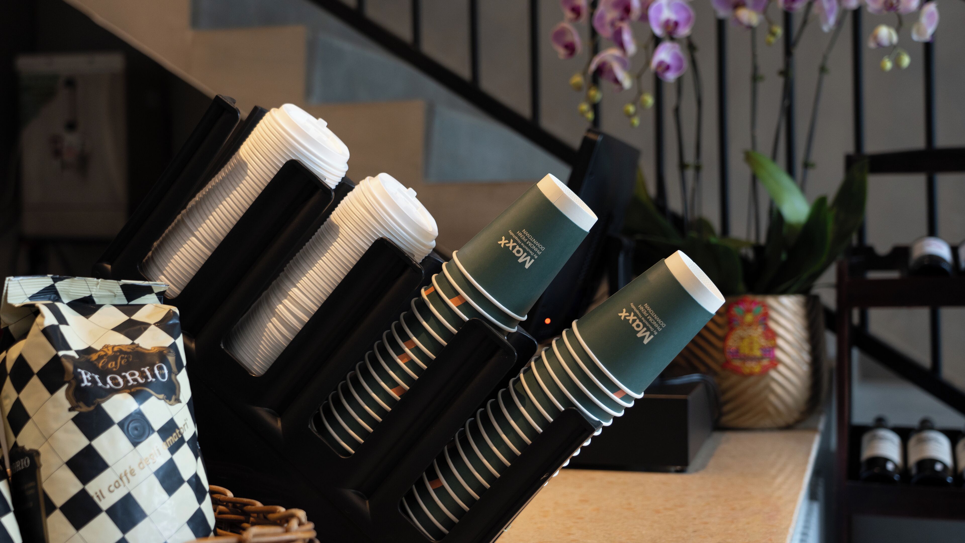 A coffee machine with multiple coffee cups and a bag of coffee beans.