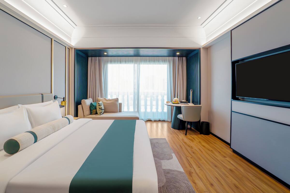 Een moderne hotelkamer met een groot bed, een bureau en een televisie.