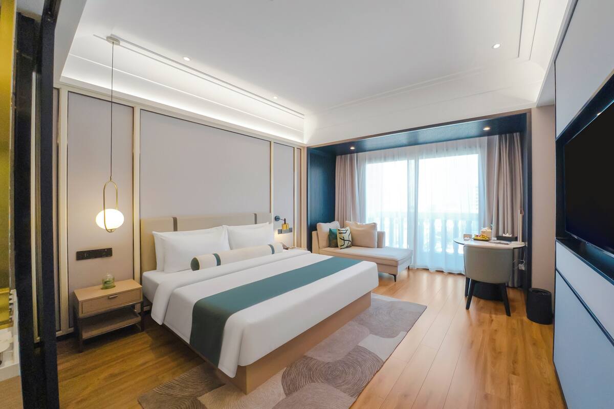 Een moderne hotelkamer met een groot bed, nachtkastjes, een bureau en een televisie.