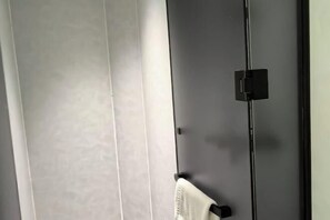 Ein Zimmer mit einem großen Fenster, einer schwarzen Tür und einem Handtuch an einem Haken.