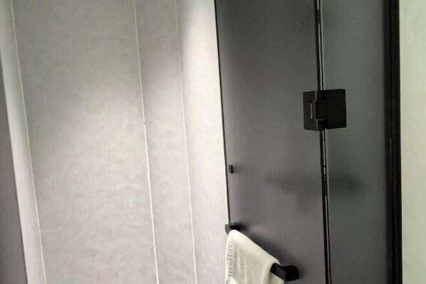 A room with a large window, a black door, and a towel hanging on a hook.