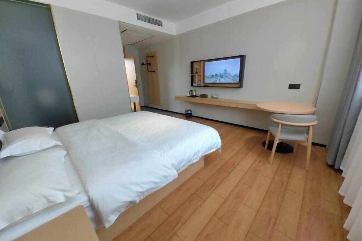 Una habitación de hotel con cama, escritorio y televisor.