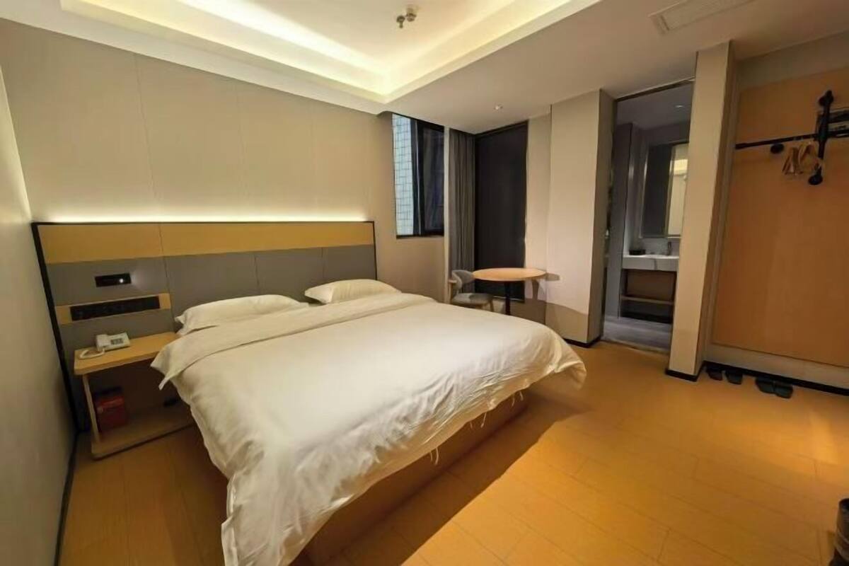 Una habitación de hotel moderna con una cama grande, una mesita de noche y un escritorio pequeño con una silla.