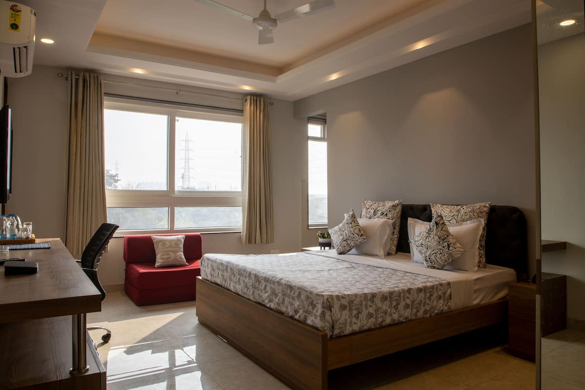 A modern hotel room with a large bed, a desk, a red sofa, and a ceiling fan.