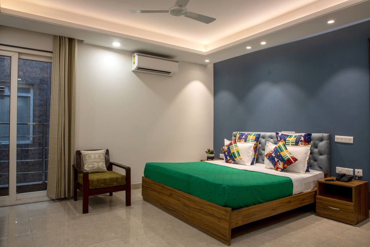 A modern bedroom with a green bedspread, a wooden headboard, and a nightstand.