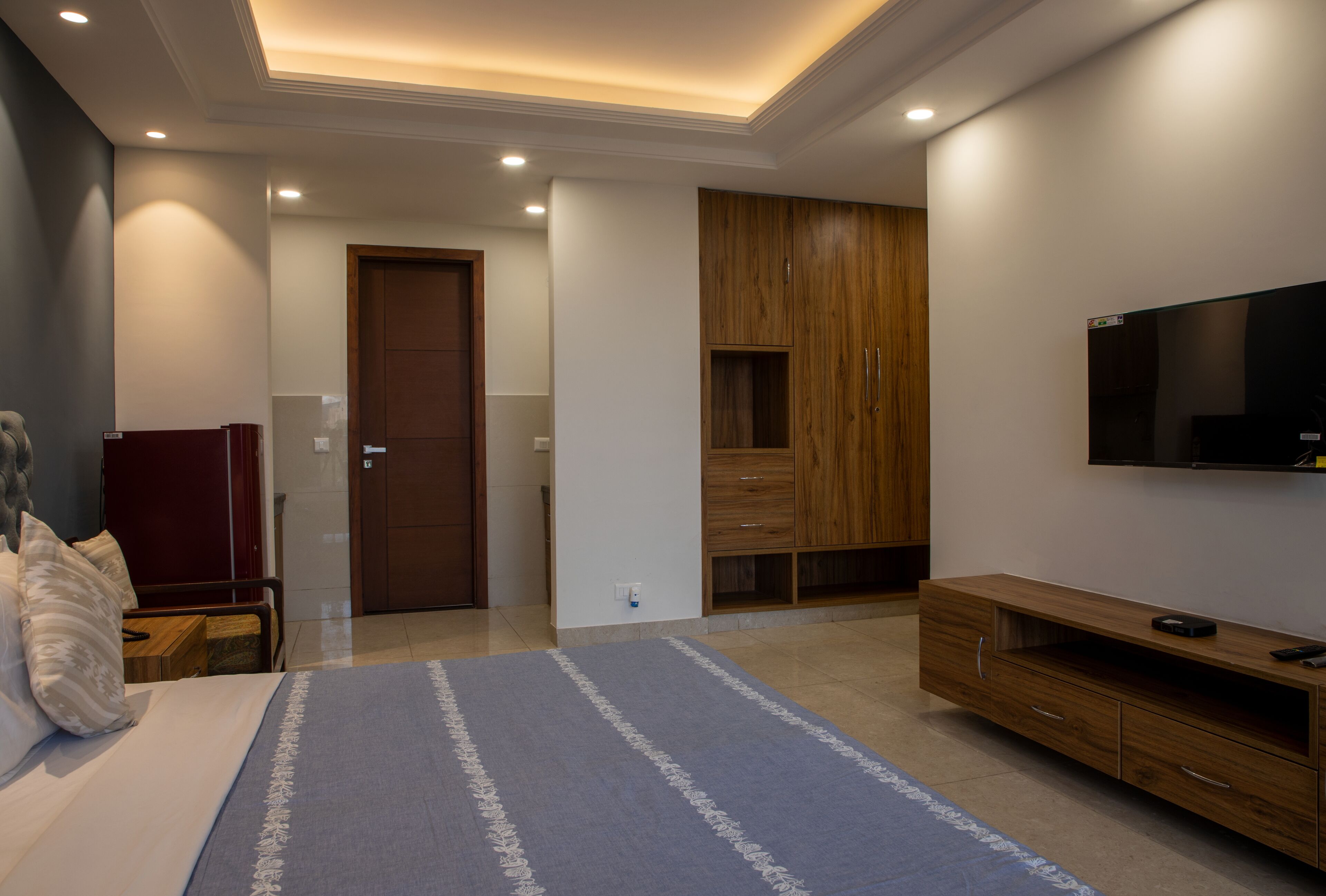 Camera da letto moderna con un letto, una TV e un armadietto in legno.