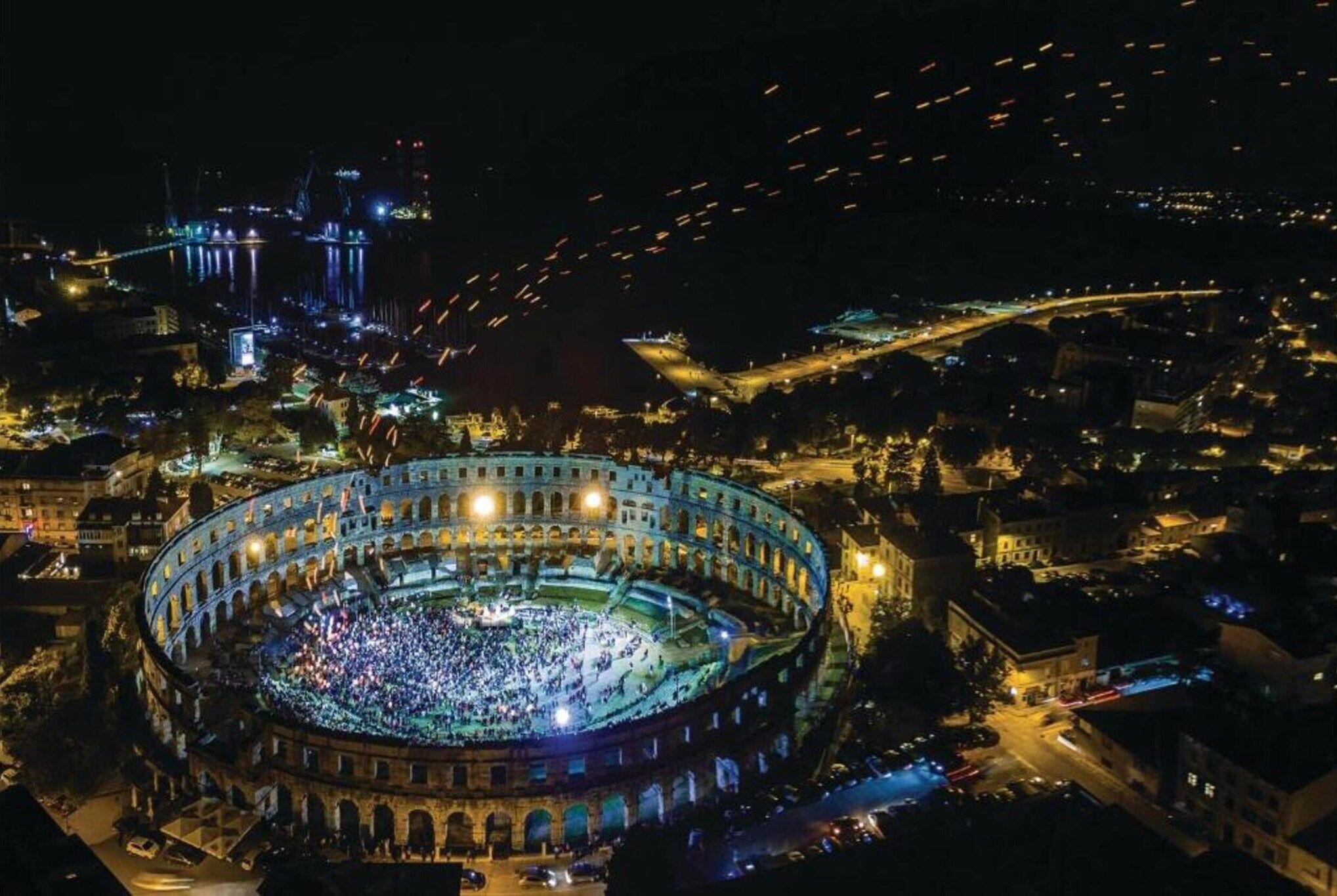 An aerial view of a historic amphitheater with a large crowd gathered inside.