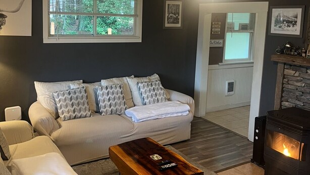 Een woonkamer met een bank, fauteuils, een salontafel, een open haard en uitzicht op de omgeving.